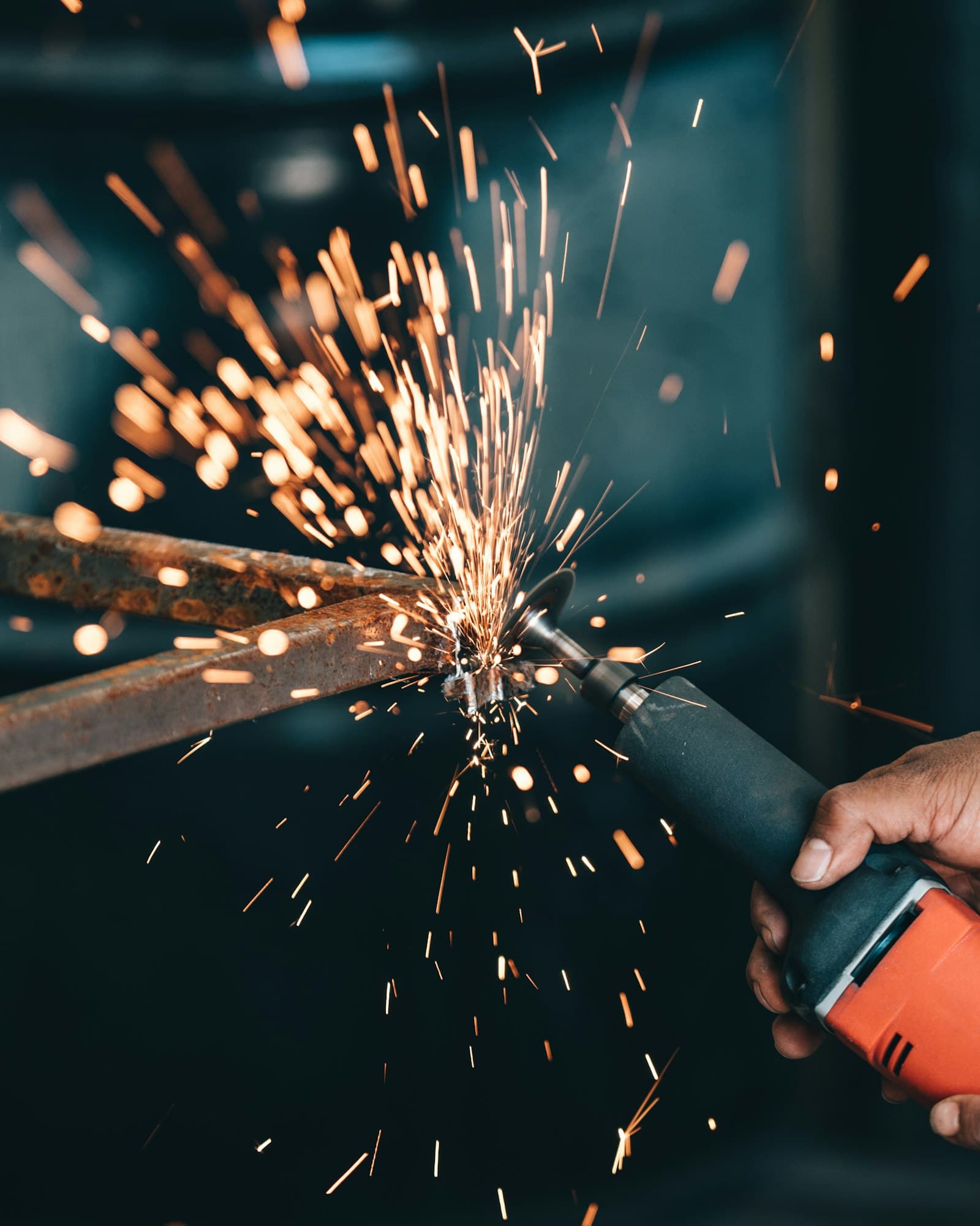 ช่างใช้เครื่องเจียรตัดเหล็ก สะเก็ดไฟกระจายเป็นวงกว้าง — งาน hot work ที่ต้องมี fire watch เฝ้าระวังไฟต่อหลังหยุดงาน