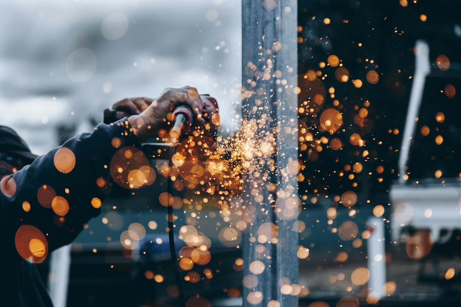 A welder at work with sparks flying — demonstrating hot work that requires welding blankets per FM Approvals 4950 standards