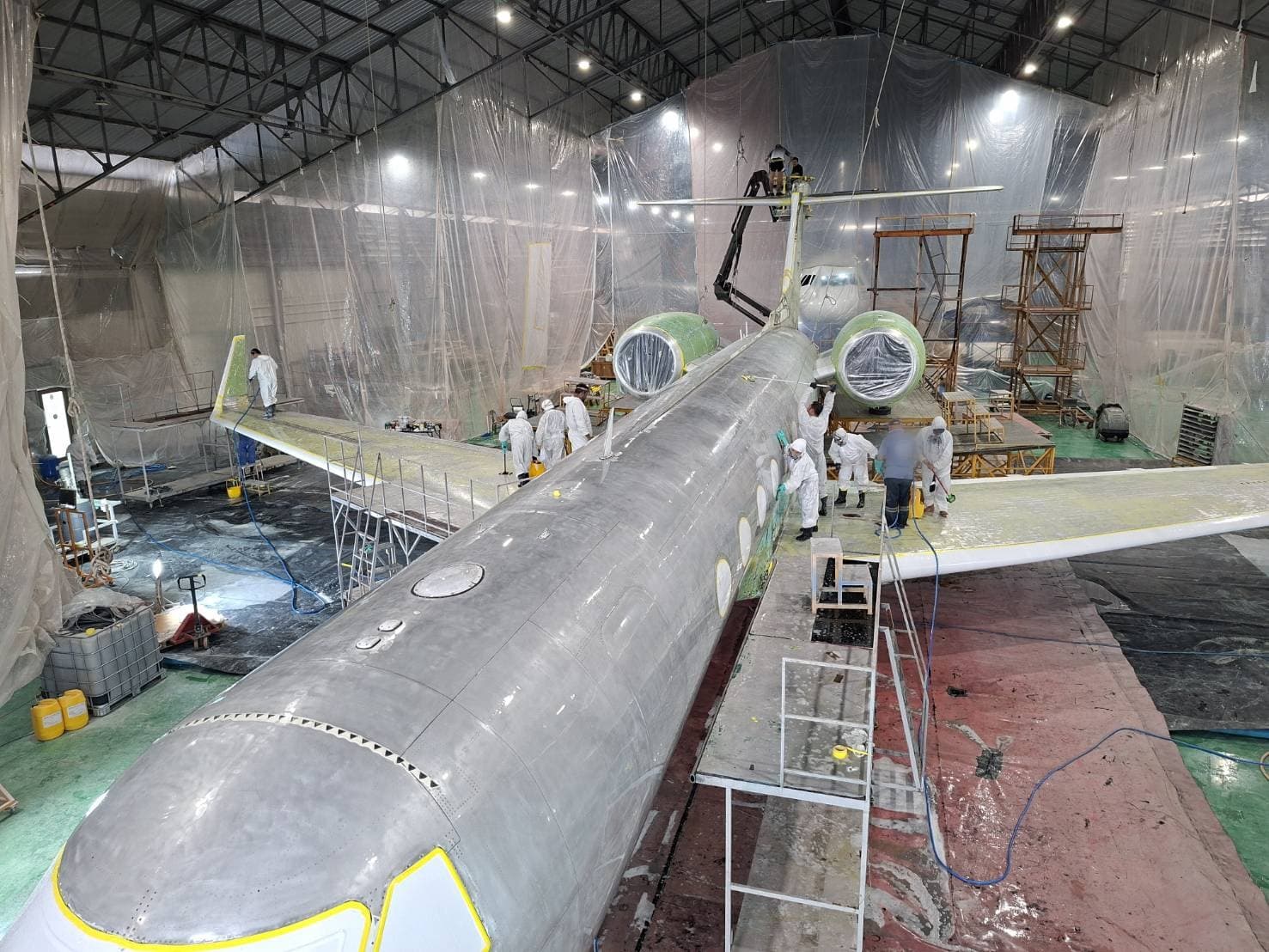 An aircraft fuselage stripped to bare metal during surface preparation with abrasives and wipe cleaner